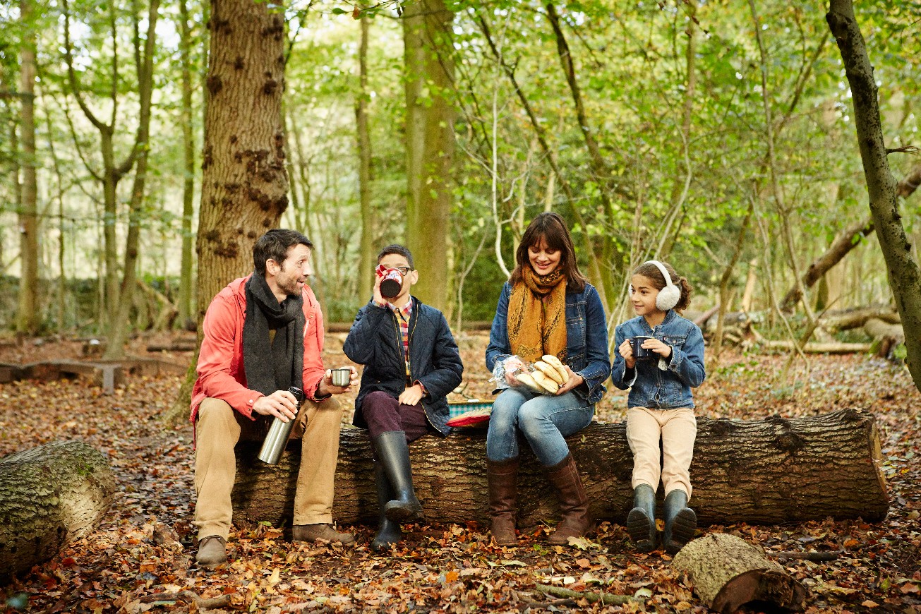 Bristol,England,Beech woods in Autumn. Parents and two children sitting on a log having a picnic.